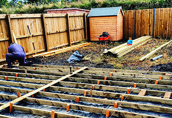 Backyard brick decking project in progress with wooden framing in Lennox.